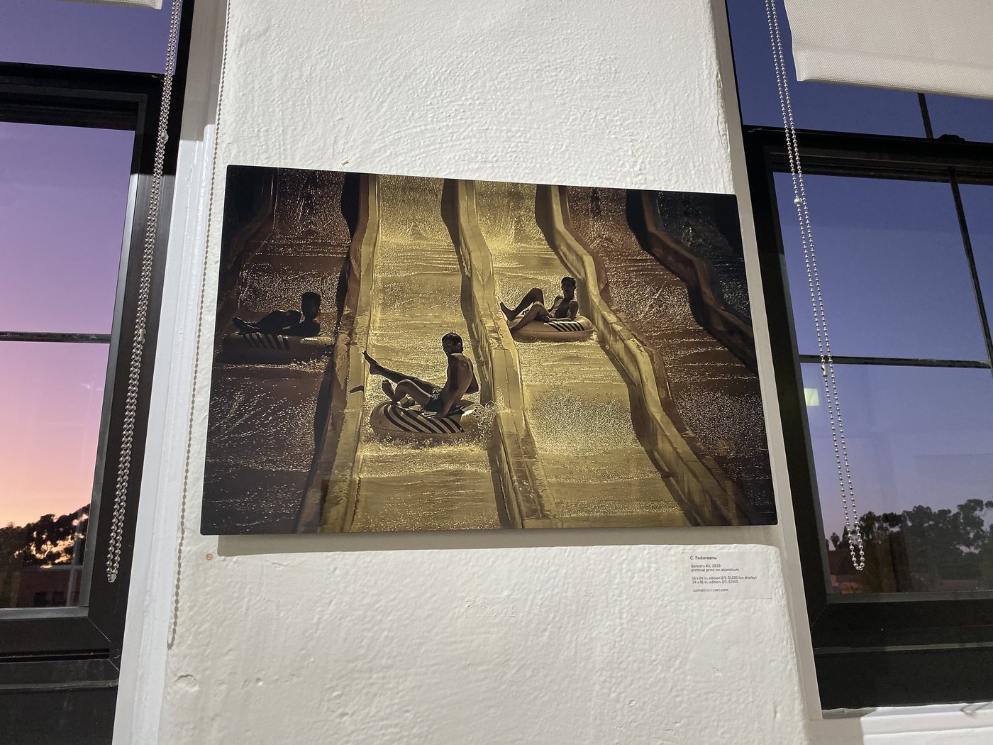 dancers, installation view at Cornel/Henry Art, San Diego, 2019 — a framed photograph of figures in the gold water-slide channels, against the windows